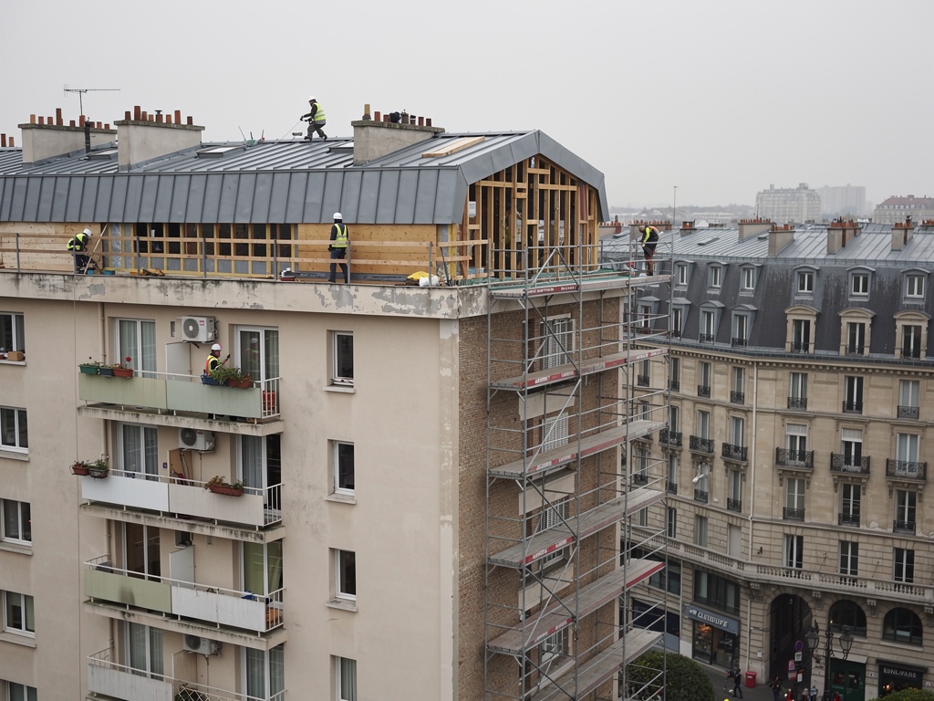 Chantier de surélévation d'un immeuble en banlieue parisienne — ajout d'un niveau en ossature bois au-dessus du bâtiment existant pour créer des logements supplémentaires sans empiéter sur le terrain