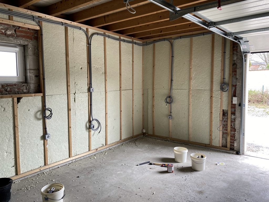 Chantier de transformation d'un garage en pièce habitable — démolition des cloisons existantes, isolation des murs et du sol, création d'une ouverture sur jardin